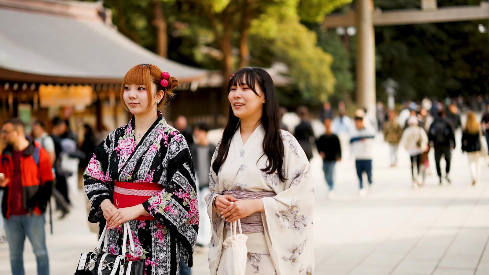 着物姿の二人の女性が、賑やかな参道を歩いている様子